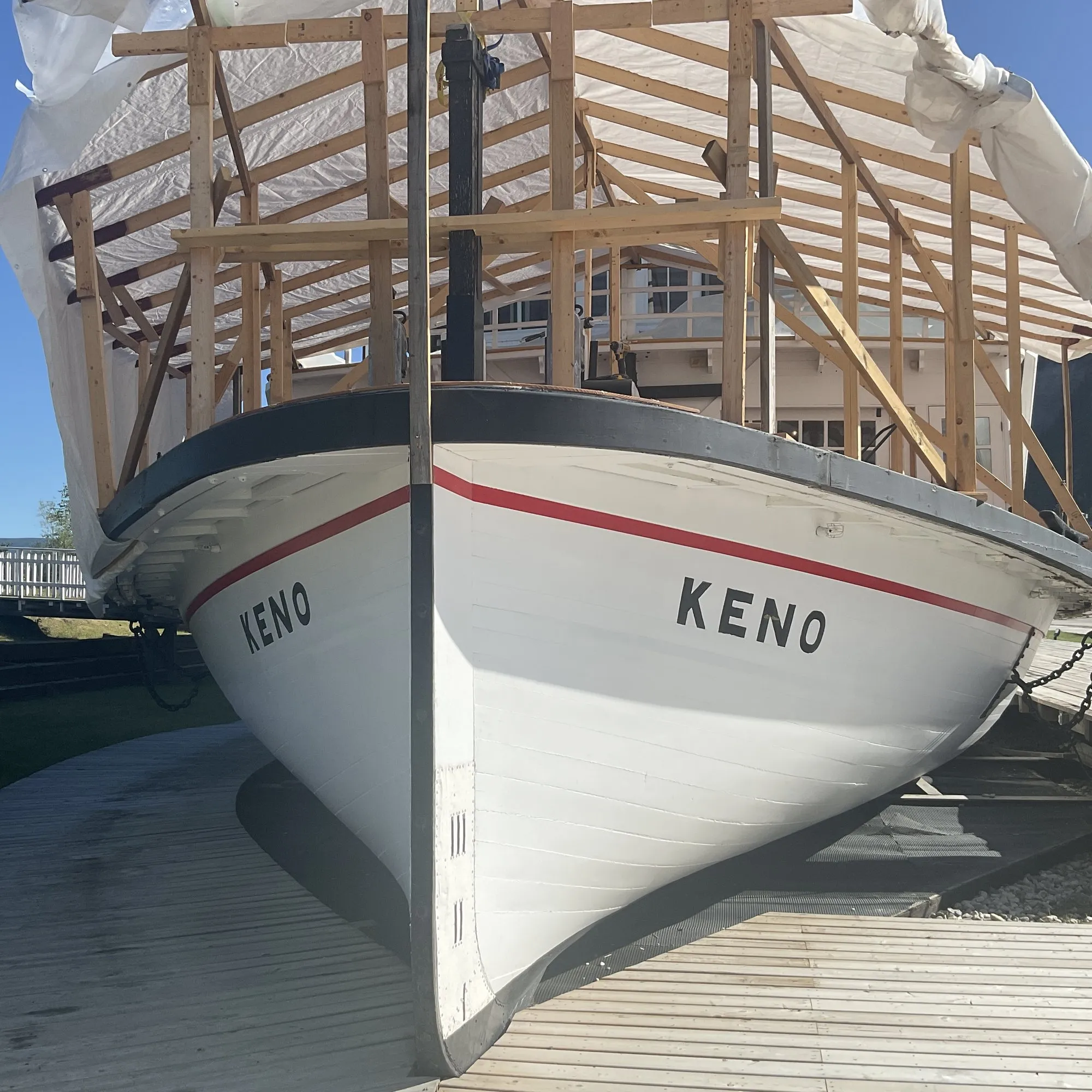 Bow of the Keno with her name on both bows, the forward main deck under a timber-framed temporary shelter