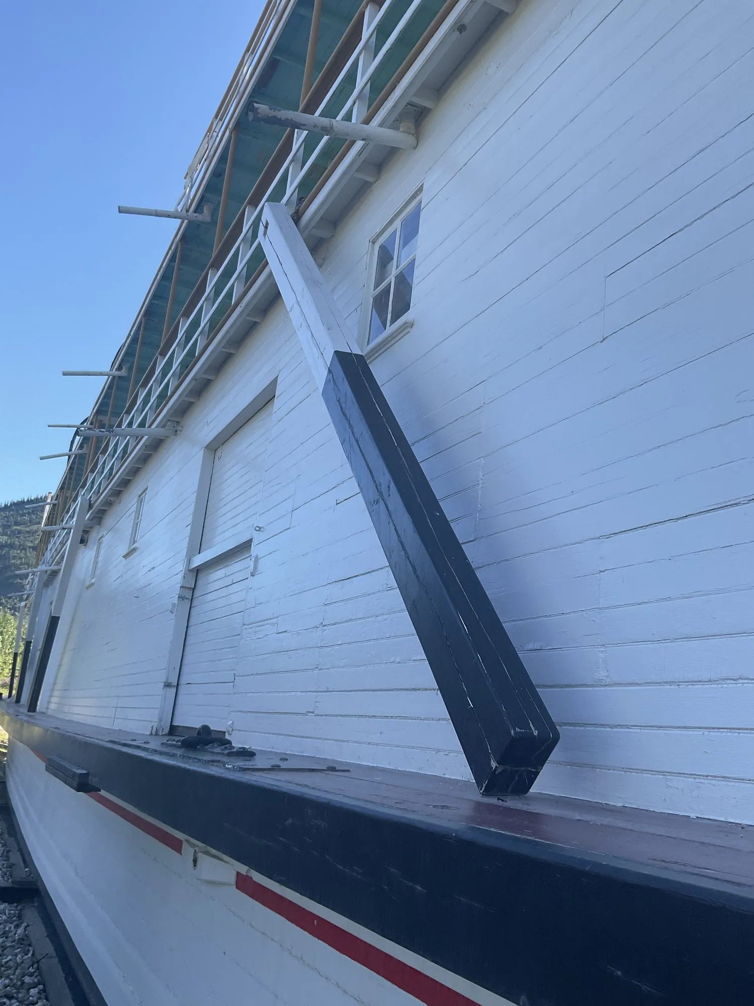 White freight-deck wall above the hull with a long diagonal timber brace against the guard