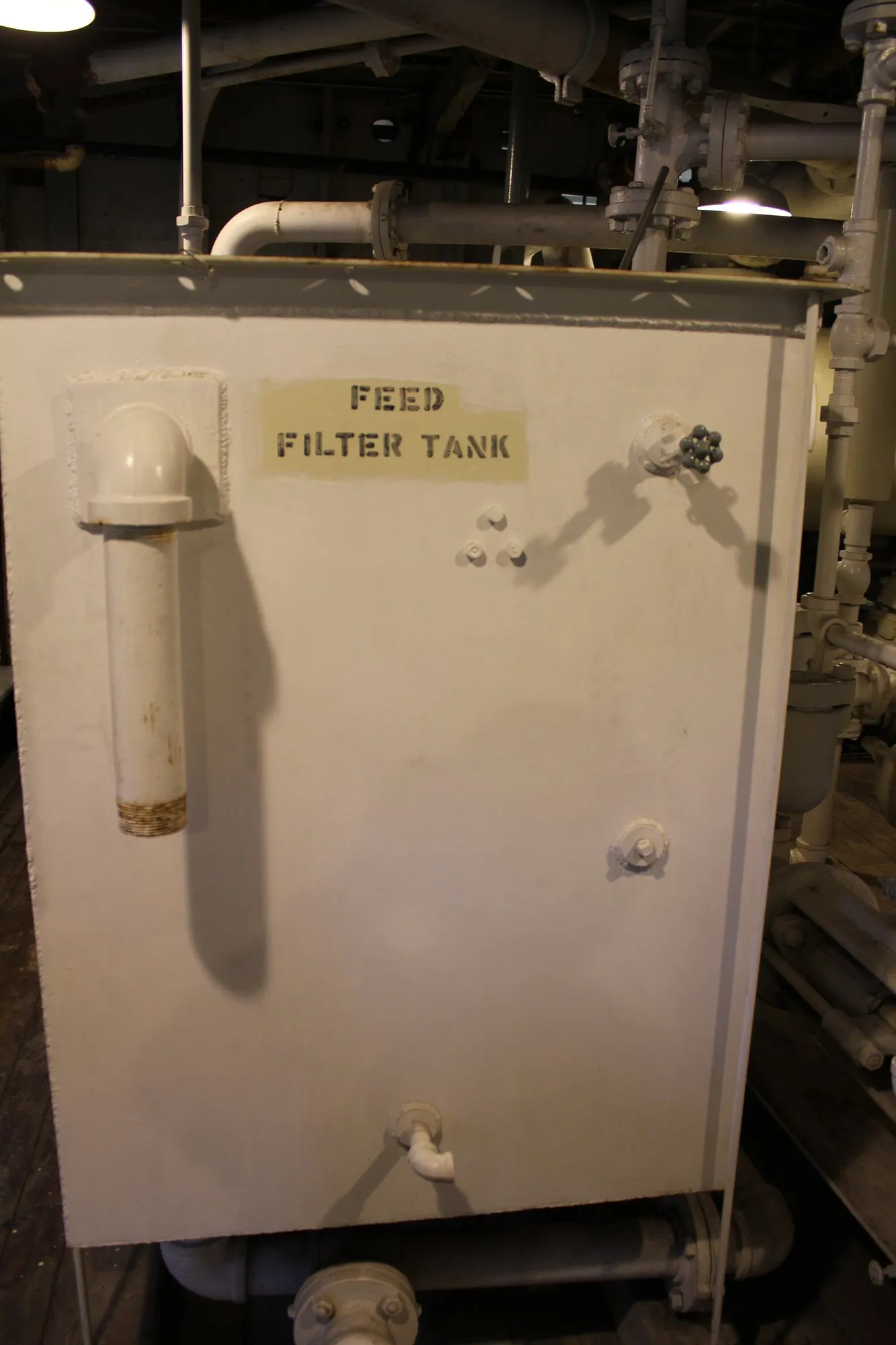 Square white tank stencilled Feed Filter Tank among piping