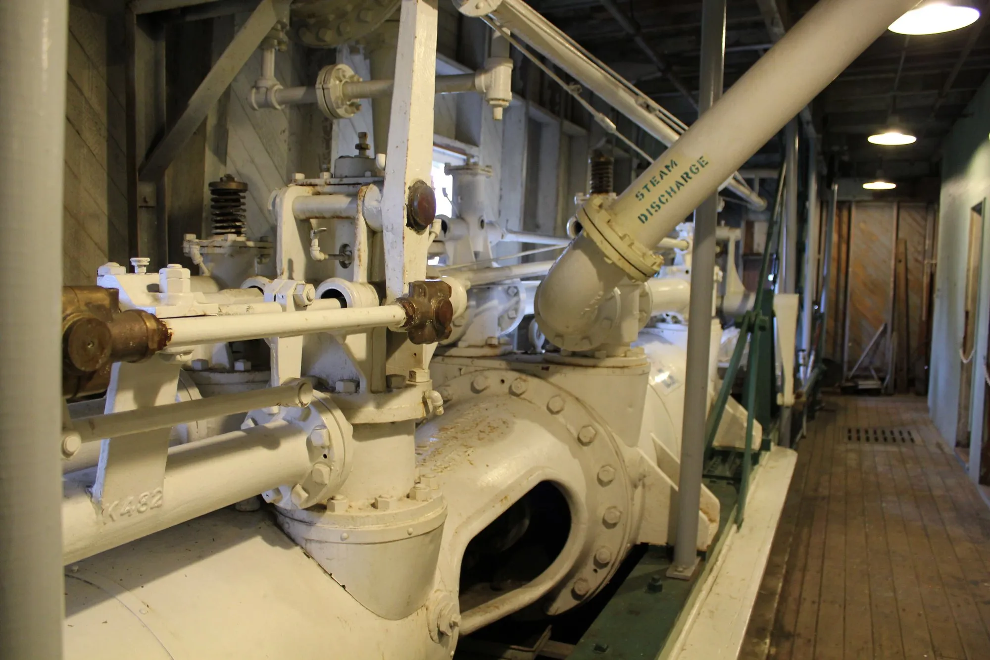 Looking aft along an engine: valve gear rods with brass fittings, the cylinder and its steam discharge pipe