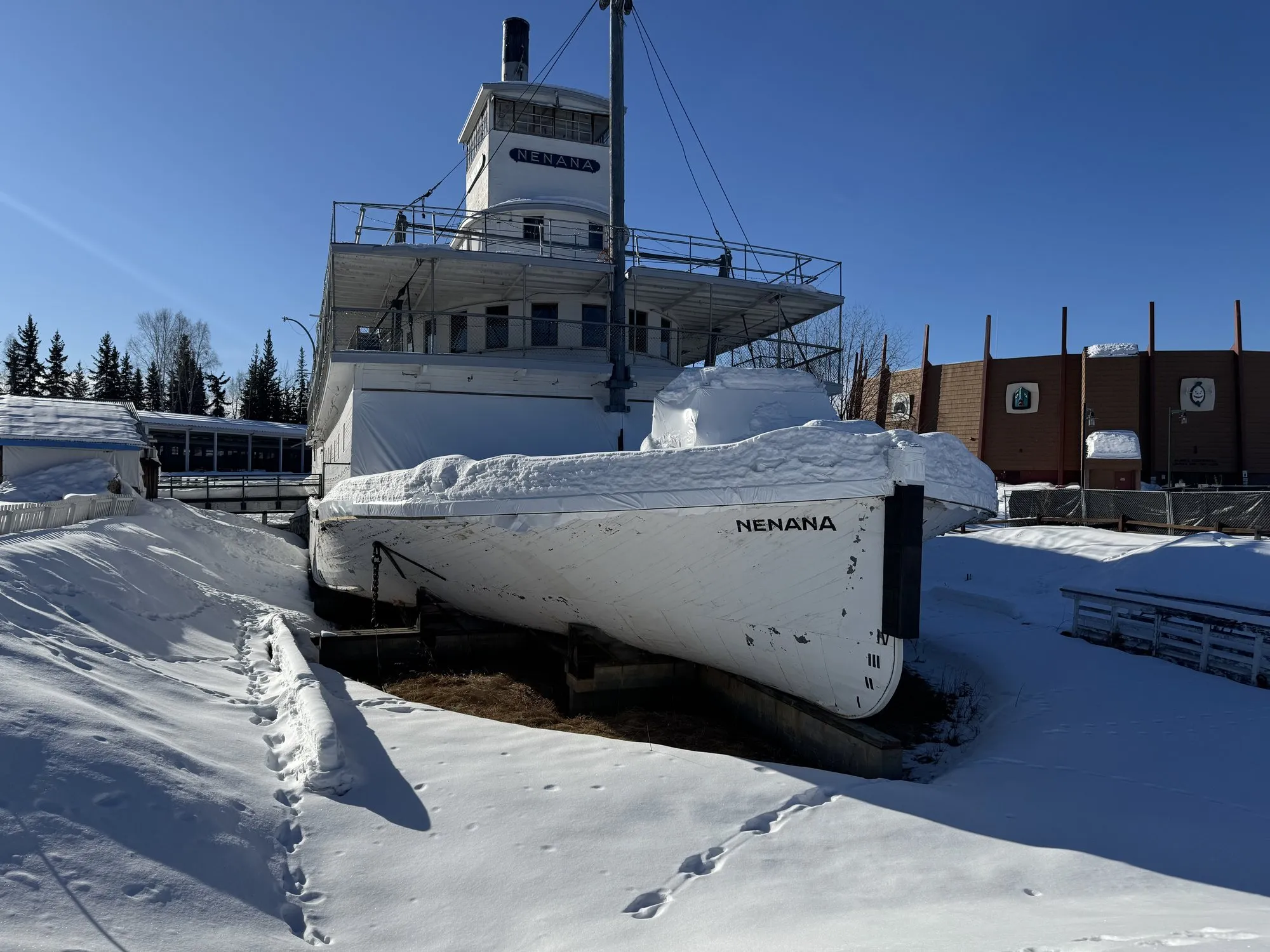 The Nenana's bow banked with snow under a clear winter sky
